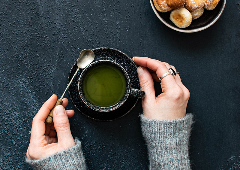 Image of a women's hands holding a cup of green tea